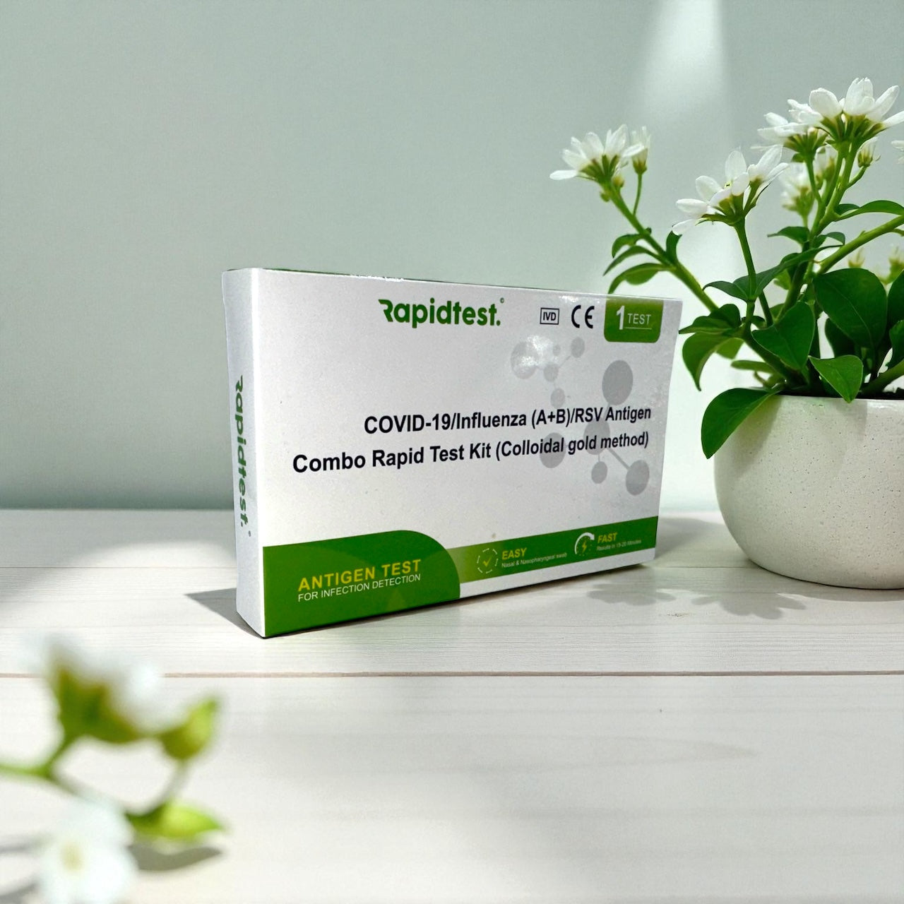 Rapidtest COVID-19/Influenza (A+B)/RSV Antigen Combo Rapid Test Kit on a white surface with a plant in the background